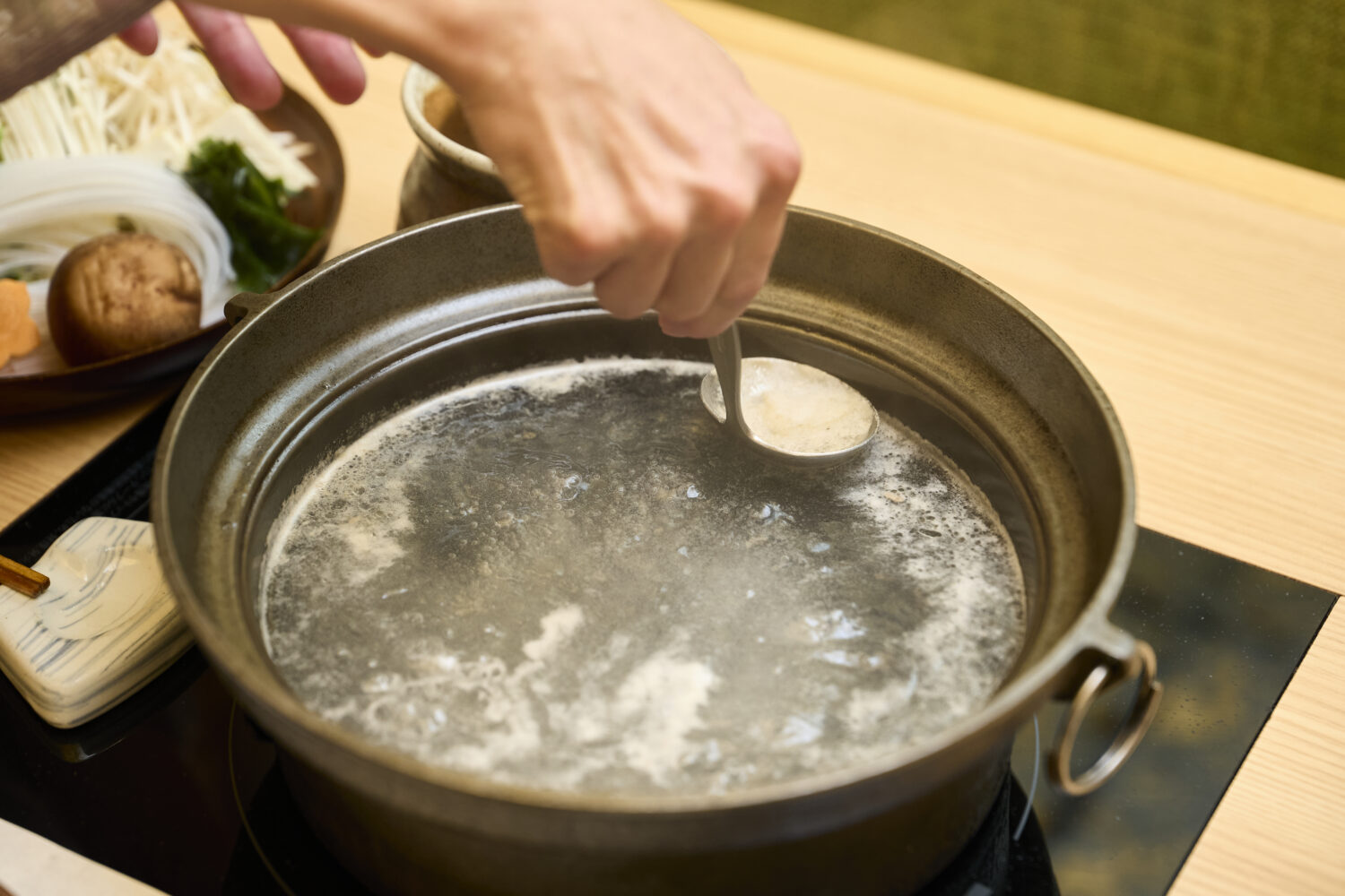 灰汁が浮かんできたら、鍋の温度をもとに戻し、レードルを使ってすくいます。